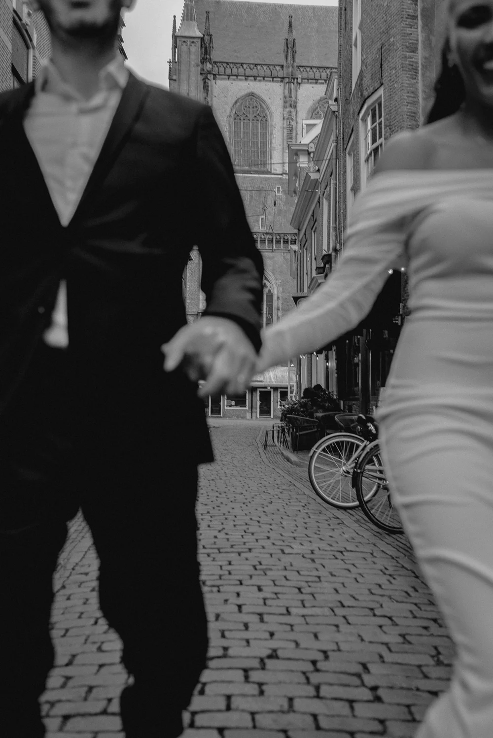 Artistic image of a couple holding hands running down the street in Haarlem Centrum after getting married.