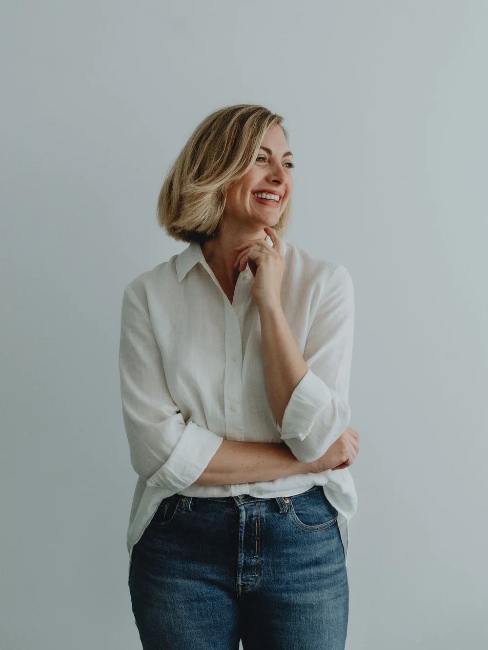 Business woman standing at a table in a white button-up shirt and a blue jean