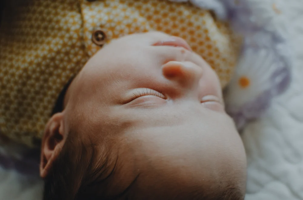 Newborn baby girl in a yellow dress, closeup photo of her eyelashes
