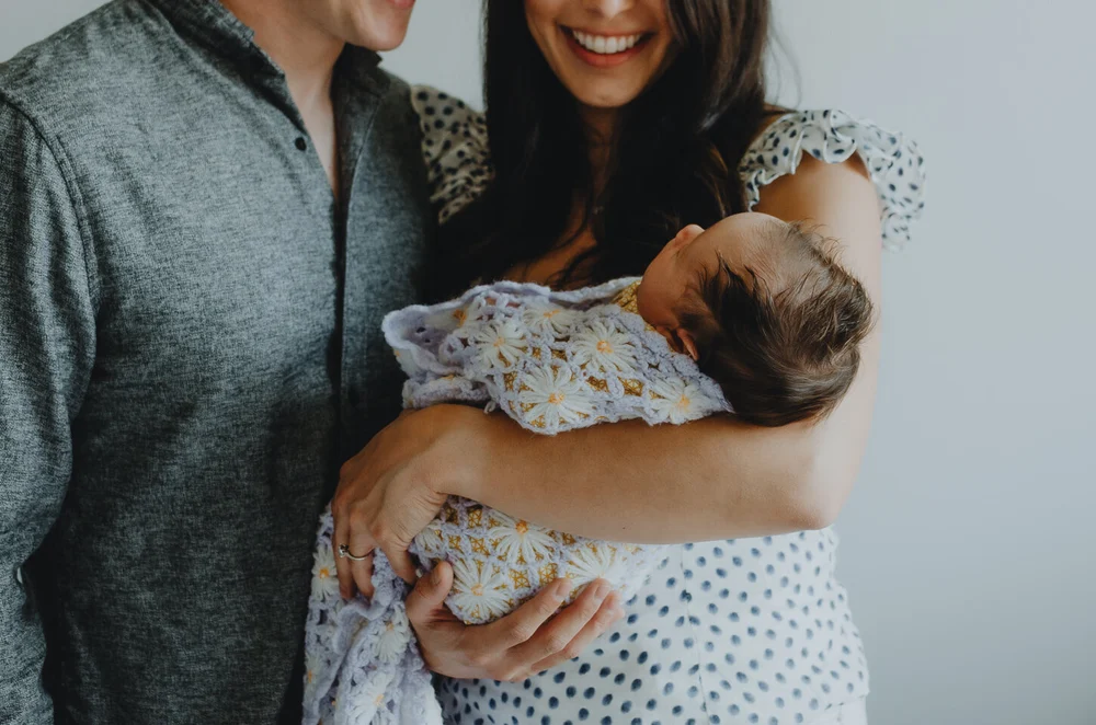 Mom and dad holding their newborn baby, closeup photo of the three of them