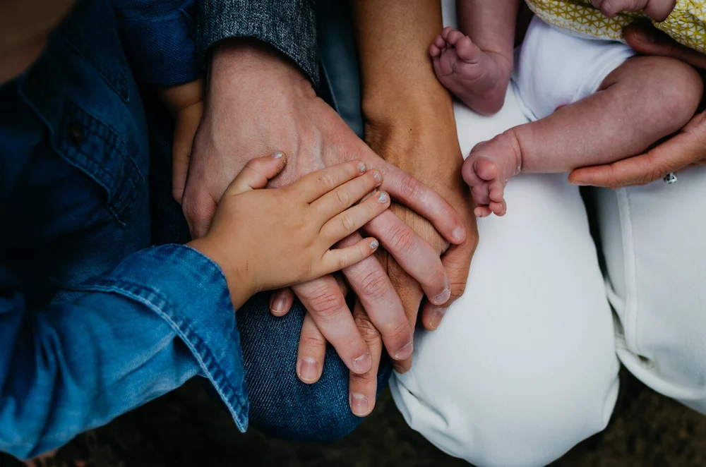 Family photo with everyone's hands holding on to each other, little baby toes can also be seen.
