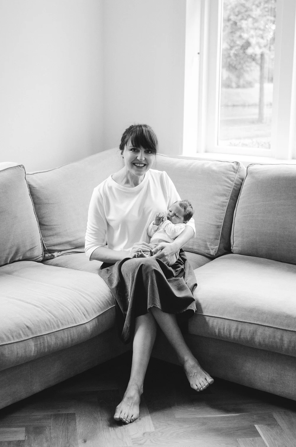 Newborn baby held by mom while they are sitting in the coach