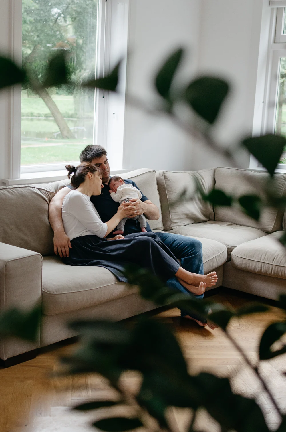 Family sitting together in the coach in the living room while holding their newborn baby