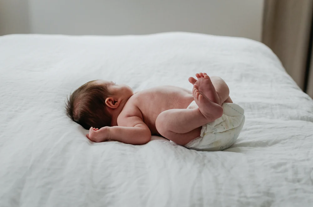 Newborn baby lying on the bed stretched out with lots of clean space around her
