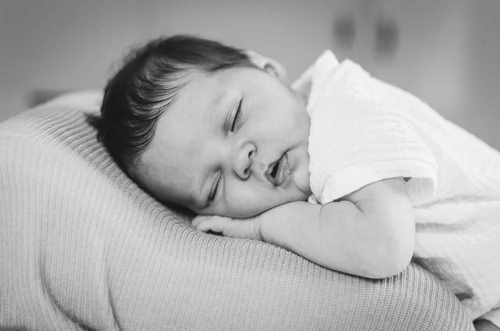 Newborn baby lying on her tummy, posed in a relaxed way while sleeping on her tummy