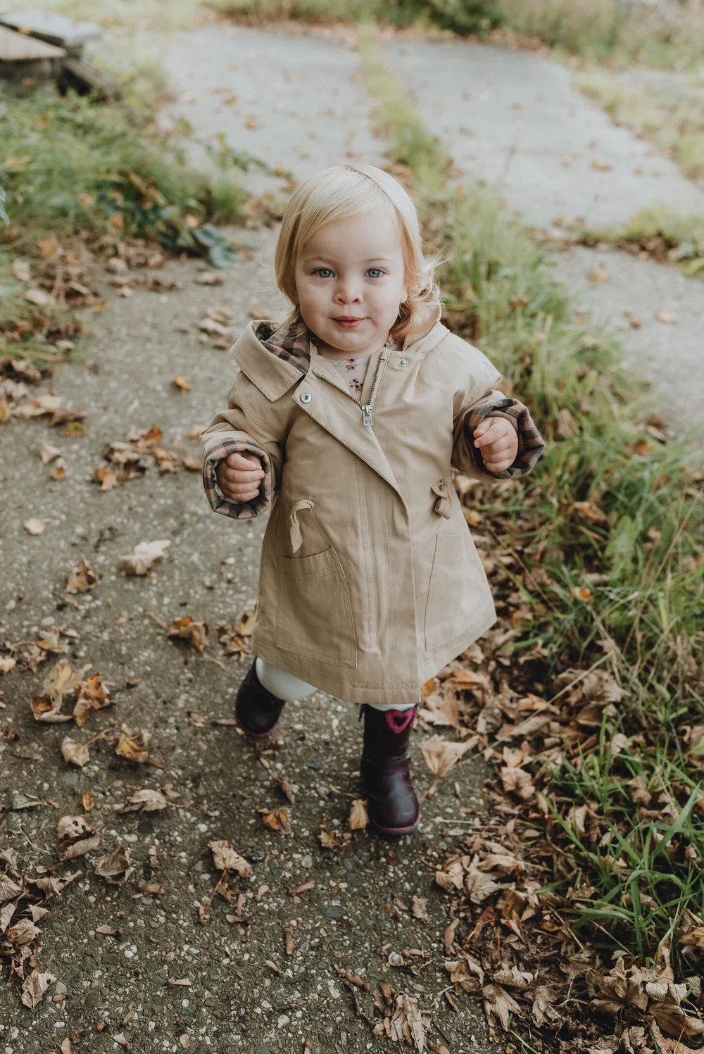 Baby girl in brown/cream coat and leather boots, during a family photoshoot in Spaarndam