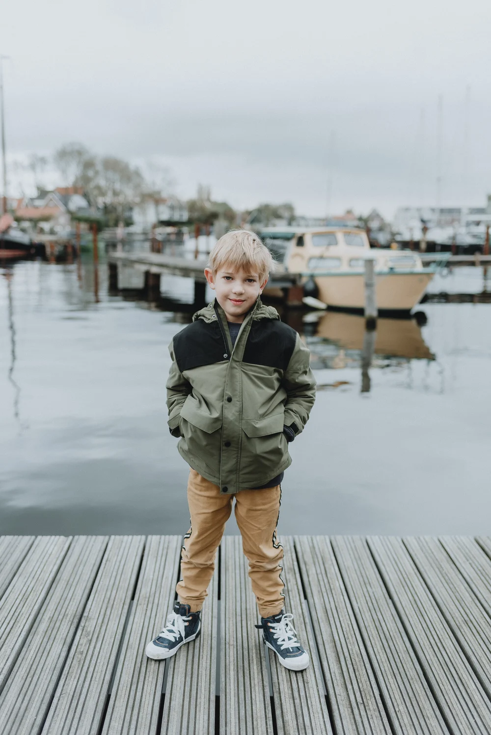 Boy standing on a bridge with boats in the background in the dock of Spaarndam, the Netherlands