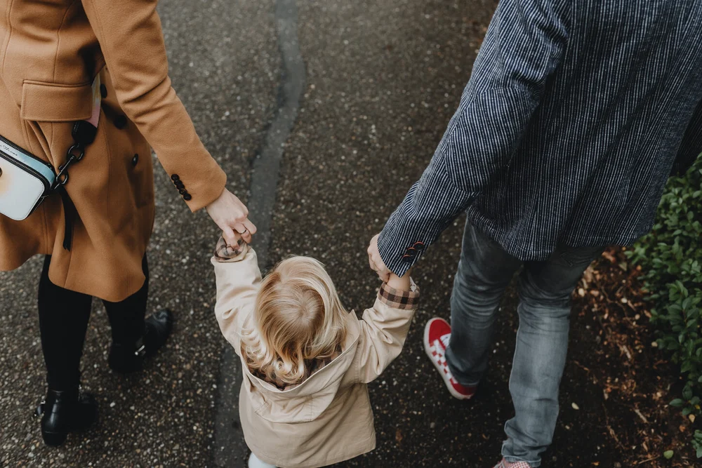 Mom and dad holding little girl's hands while walking