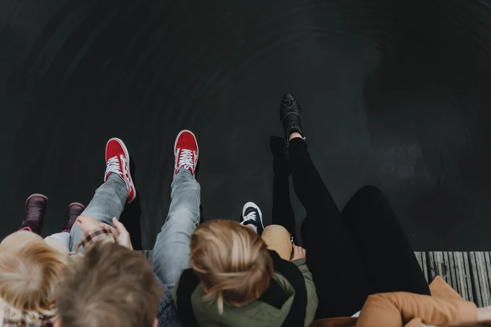 Sitting on the dock next to water with feet hanging over, image taken from the top