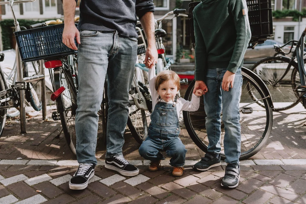 Family next to the Amsterdam canal in front of bikes