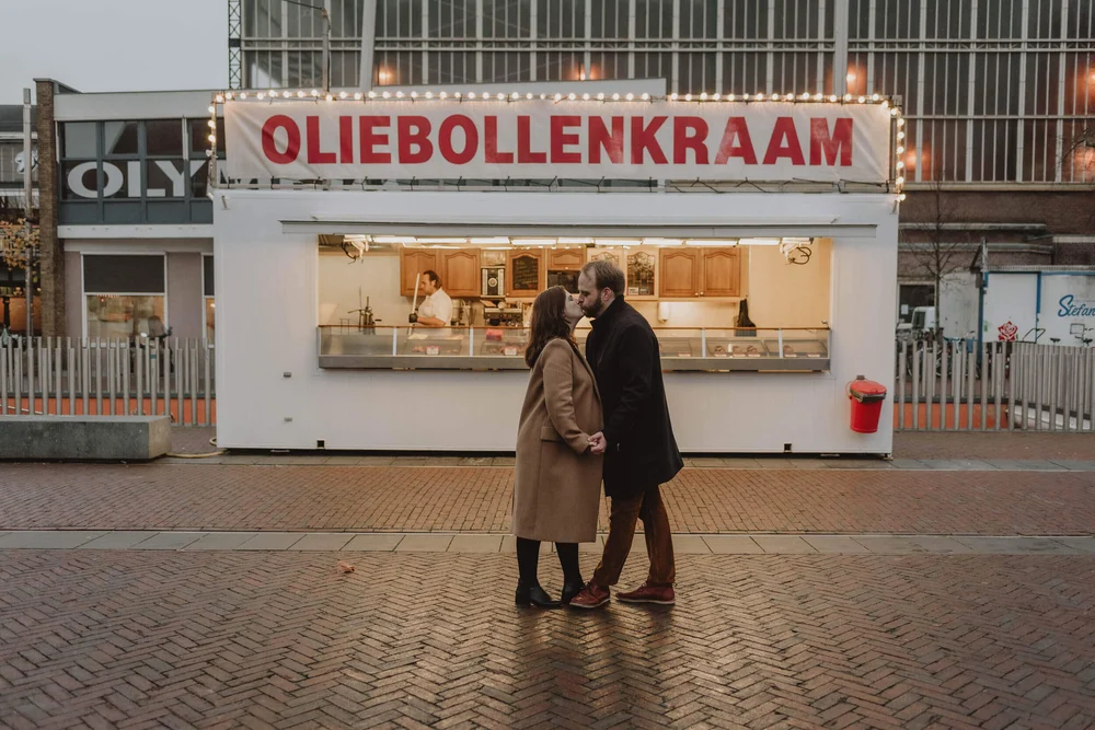 Pregnant couple standing in front of a Oliebollenkraam in the city of Haarlem