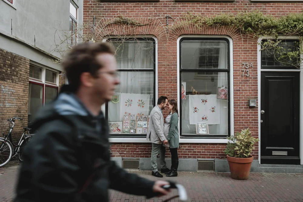 Pregnant mom and dad standing together in front of a Dutch house.
