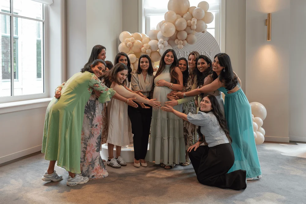Friends standing around the pregnant mother during her baby shower at the Pillows Maurits at the Park Hotel.