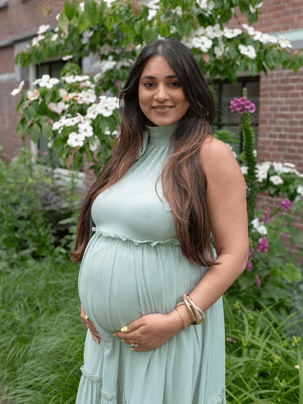 Pregnant mommy in a green dress standing next to flowers in front of the Pillows Maurits at the Park Hotel.